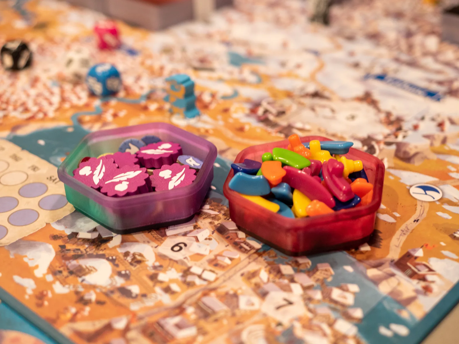 Two token holders in purple and red, holding tokens on a printed map board